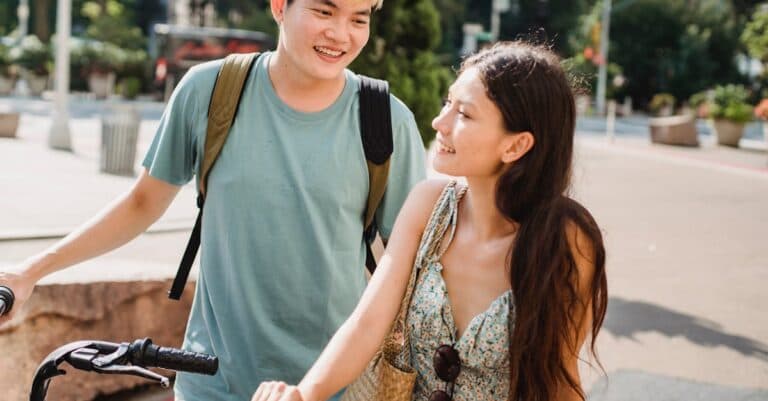 Places & Attractions Blogs | Articles | News | Tips & Tricks | Video | FAQ | Information | Infograph. 3 Cheerful multiracial couple in casual clothes walking with bicycles on city street in daylight