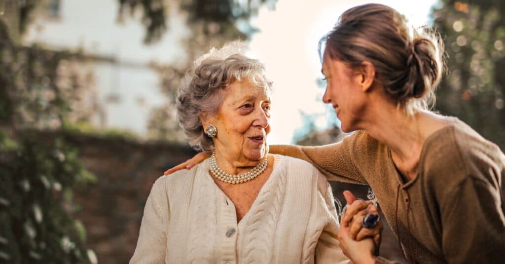 book black car service: Enhance Your Travel Experience with JetBlack 3 Elderly woman and adult daughter share a joyful, affectionate moment in a sunny garden.