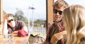 Three friends relaxing at an outdoor cafe in Australia, enjoying leisure time together.