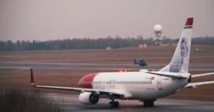 A commercial airplane preparing for takeoff at Vilnius Airport with a radar tower in the background.