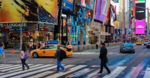 Times Square pedestrian crossing with billboards and taxis, capturing New York City's energy.