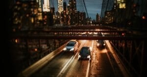 Dynamic night view of Brooklyn Bridge with cars and city skyline in New York City.