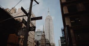 Low angle view of the Empire State Building amidst New York City's urban architecture and street signs.
