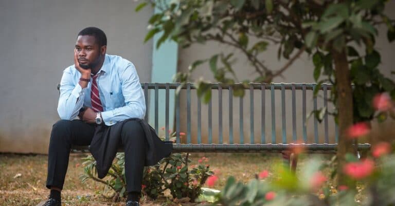 New Jersey Blogs | Articles | News | Tips & Tricks | Video | FAQ | Information | Infograph. 22 A businessman in a suit sits pensively on a bench in a tranquil park setting.