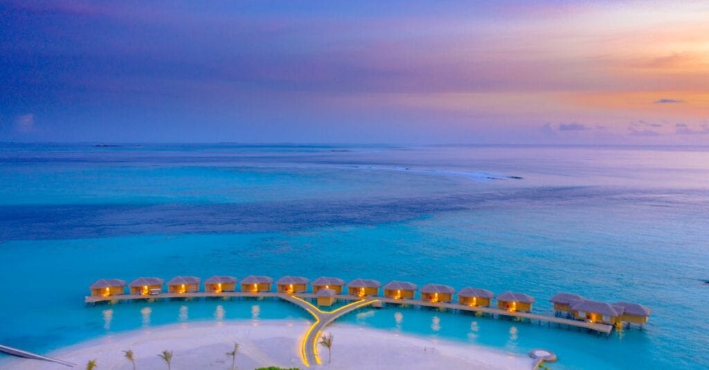 A breathtaking aerial shot of overwater bungalows in the Maldives during sunset.