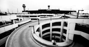Dramatic black and white view of a spiral parking ramp at Chicago's O'Hare Airport with Hilton hotel in background.