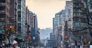 Bustling New York City street with skyscrapers at dusk, featuring yellow cabs and city life.