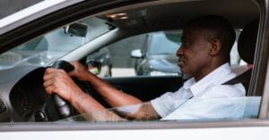 Side view of an adult man driving a car, embodying focus and concentration.
