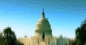 Artistic reflection of the US Capitol on a clear, sunny day over rippling water.