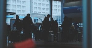 Silhouetted travelers wait with luggage in a Japanese railway station, focusing on transportation and travel.