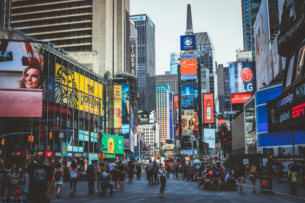 Featured image of a luxury black SUV for LaGuardia to Manhattan transport pulling up at Terminal B, with the glittering Manhattan skyline visible across the East River at dusk in 2025.daytime view of Times Square with crowds, skyscrapers, and iconic billboards in New York City.