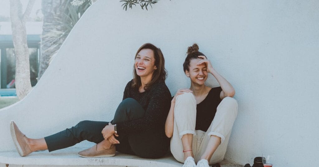 Two women laughing together outdoors, enjoying leisure time and friendship.