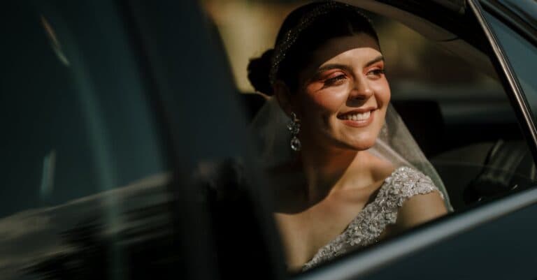 Radiant bride smiling from limousine window, capturing a joyful wedding moment.