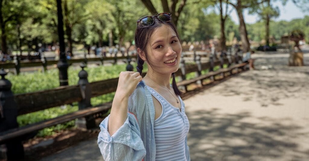 Young woman enjoying a sunny day in Central Park, New York City, surrounded by lush greenery.