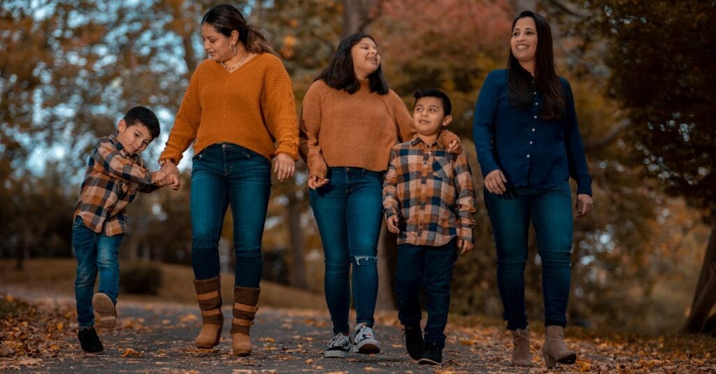 A family strolls through a park, enjoying the vibrant fall foliage.