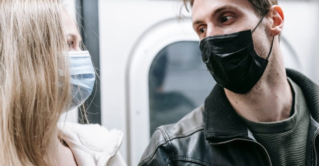 Couple wearing masks engaging in conversation on a subway. New normal lifestyle.