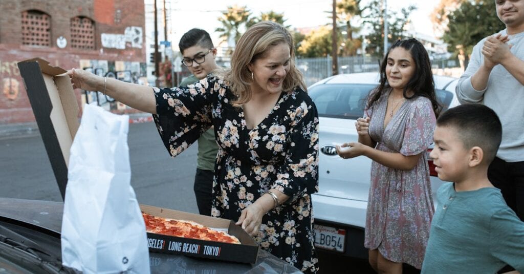 Happy family enjoying a pizza outing together in an urban setting.