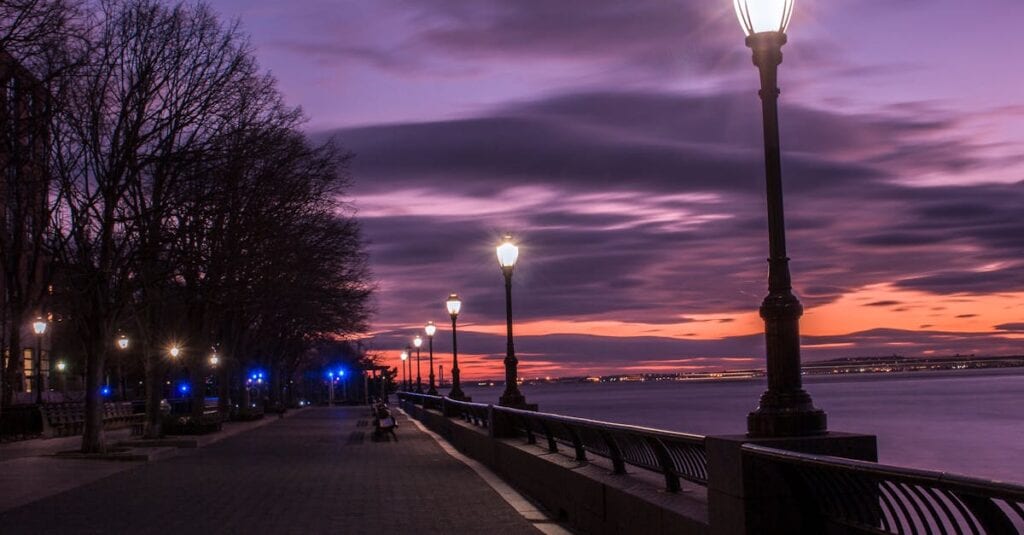 Dusk view of lamppost-lit path by the river at Robert Wagner Park, NYC.
