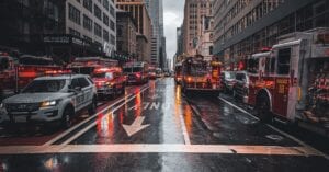 Firetrucks and police cars respond to an emergency on a wet street in New York City.