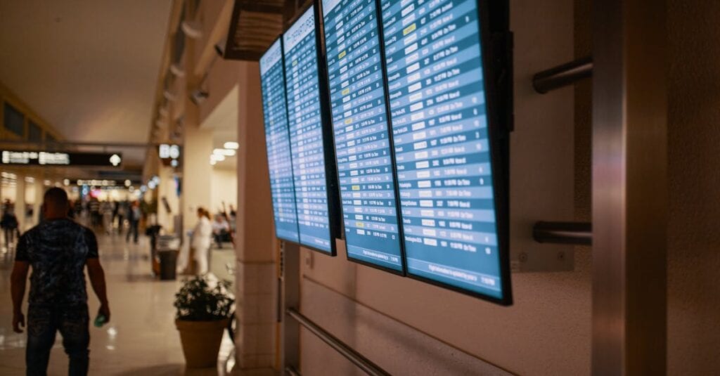 Airport terminal with digital flight information boards showing arrivals and departures.