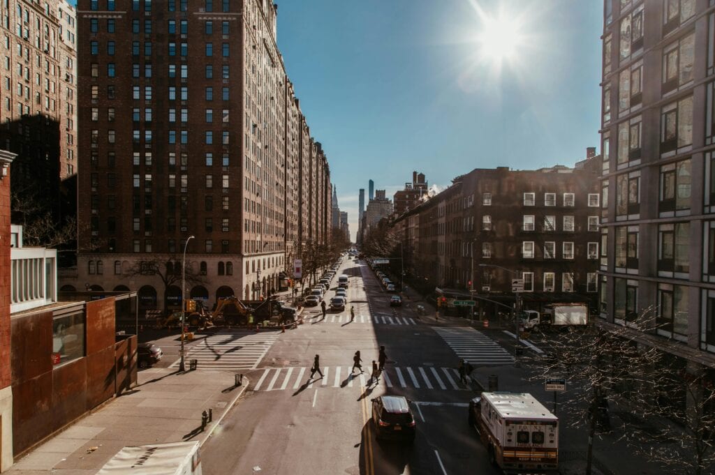 Busy New York City street scene featuring skyscrapers, traffic, and pedestrians in daylight.