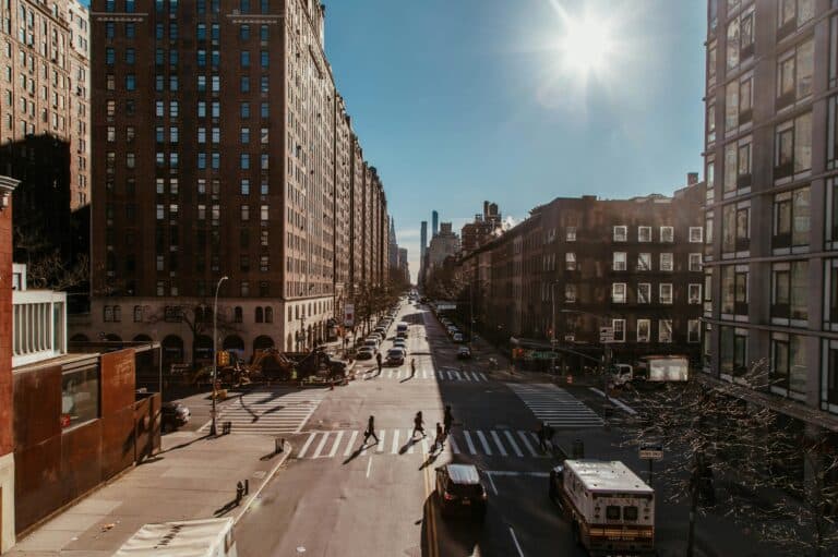 Busy New York City street scene featuring skyscrapers, traffic, and pedestrians in daylight.