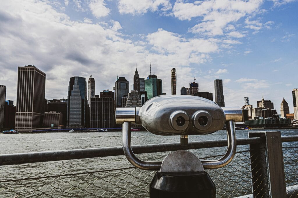 Viewfinder overlooking iconic city skyline with skyscrapers and river on a sunny day.