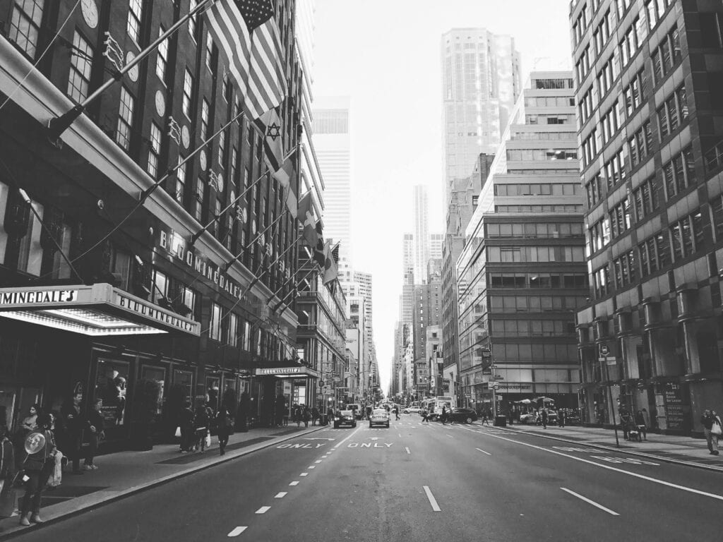 A black and white street view of Manhattan, New York City with iconic architecture and bustling life.