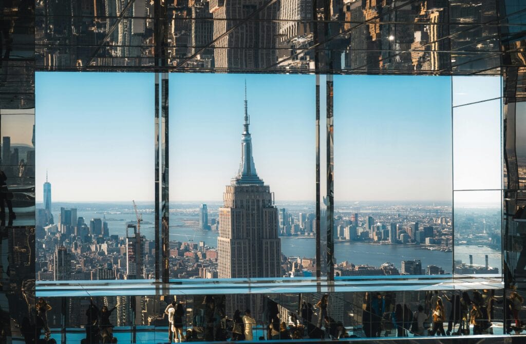 An aerial view of the Empire State Building through reflective glass, capturing New York City's iconic skyline.