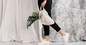 Woman in minimalist outfit holding an eco-friendly mesh bag filled with flowers, showcasing sustainable fashion.