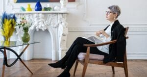 A mature woman sits pensively in a chic interior, embodying elegance and tranquility.
