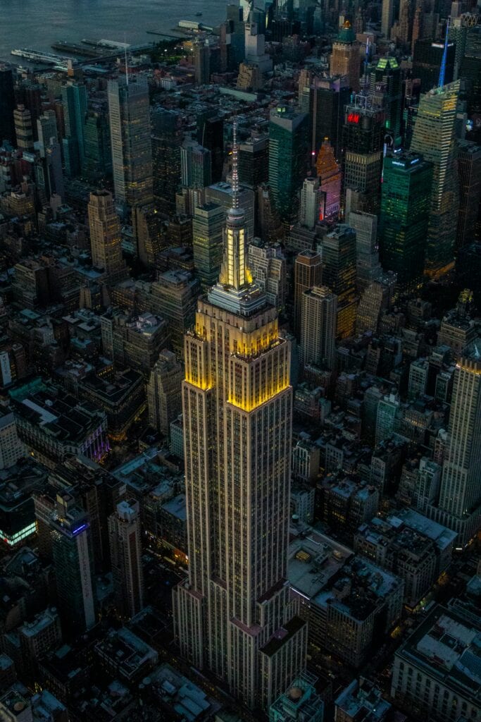 Stunning aerial view of Empire State Building illuminating New York City skyline at night.