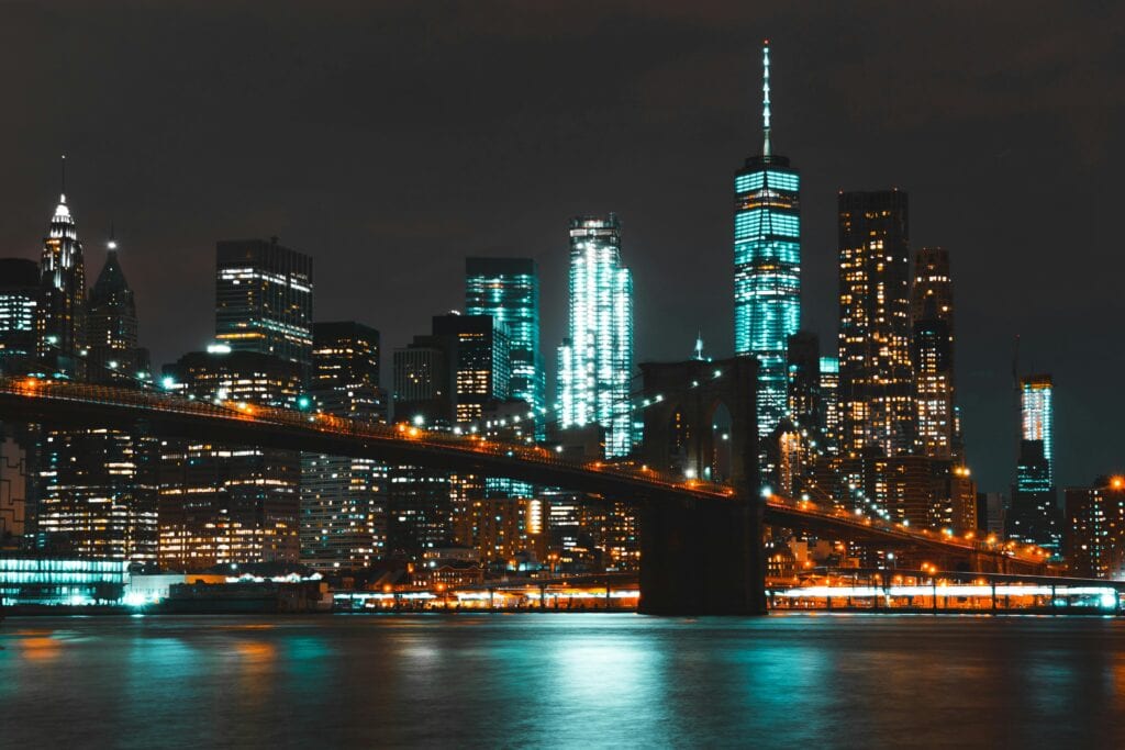 Captivating night skyline of New York City with Brooklyn Bridge and skyscraper reflections.