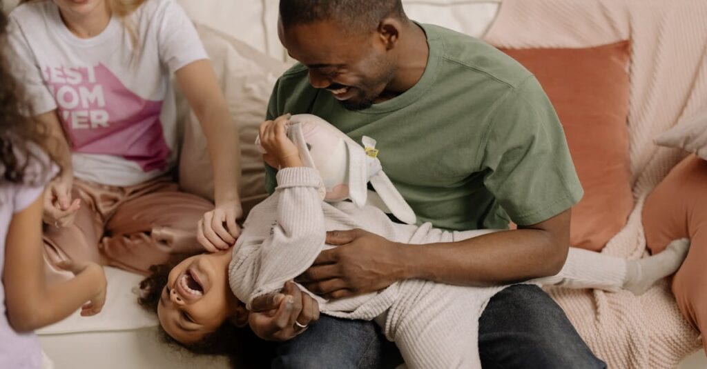 A joyful family spending quality time together playing on the sofa.