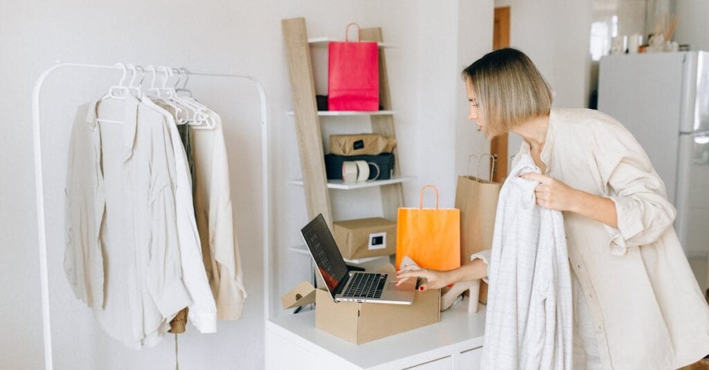 A woman in casual attire unpacking a delivery box with clothing at home, engaging in online shopping.