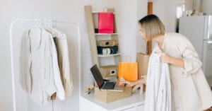A woman in casual attire unpacking a delivery box with clothing at home, engaging in online shopping.