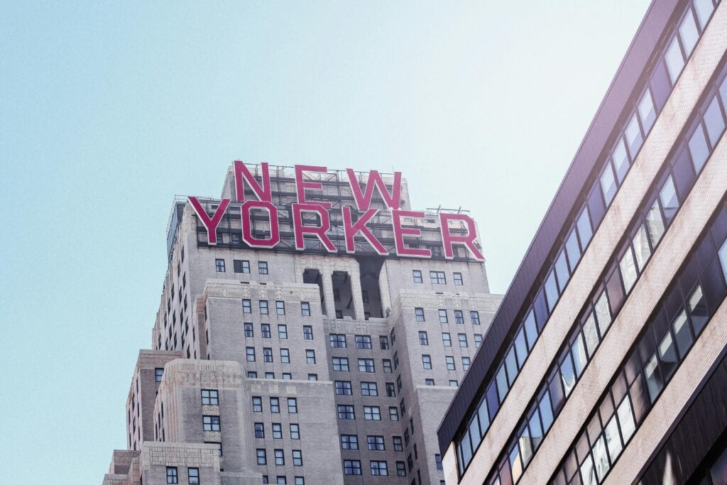 Low-angle view of the New Yorker Hotel showcasing its iconic sign against a clear sky in New York City.