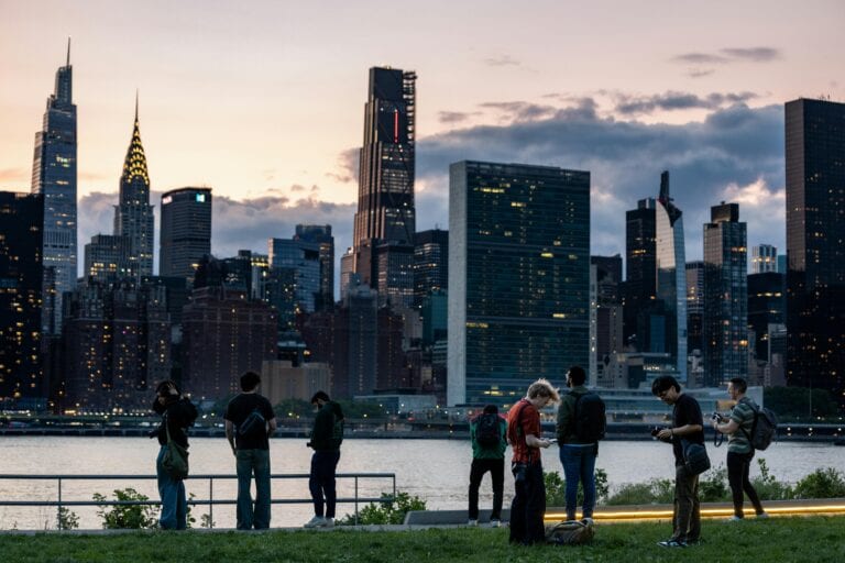 Group of people enjoying city skyline view at sunset in New York City.