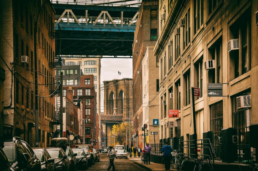 Urban view of a Brooklyn street under the bridge with city life and architecture.