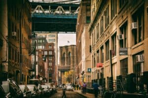 Urban view of a Brooklyn street under the bridge with city life and architecture.