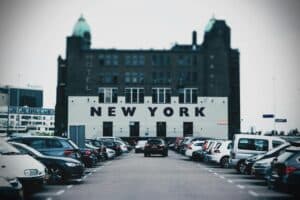 View of a parking lot with cars and a building featuring bold New York text.