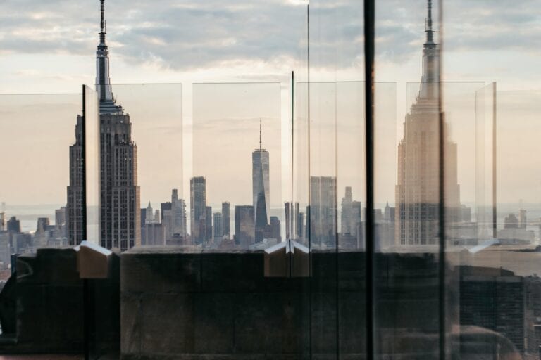 Through fenced rooftop view of skyscraper facade under cloudy sky in New York City