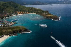 Stunning aerial view of Bali's coastline, showcasing ferries on crystal blue waters. Perfect for travel inspiration.