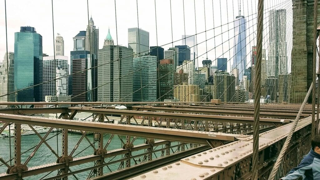 Iconic view of Manhattan skyline from Brooklyn Bridge on a clear day.