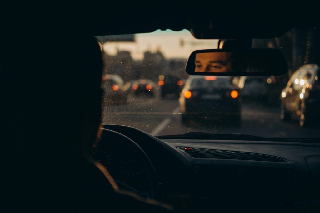 Capturing the reflection of a driver amidst evening traffic in Українка, creating a moody urban scene.