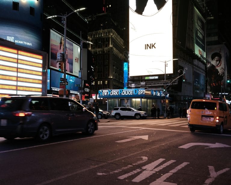 Dynamic shot of Times Square at night with bustling traffic and iconic neon signs.
