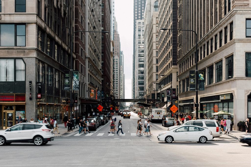 Dynamic cityscape showcasing pedestrians walking among skyscrapers and vehicles.