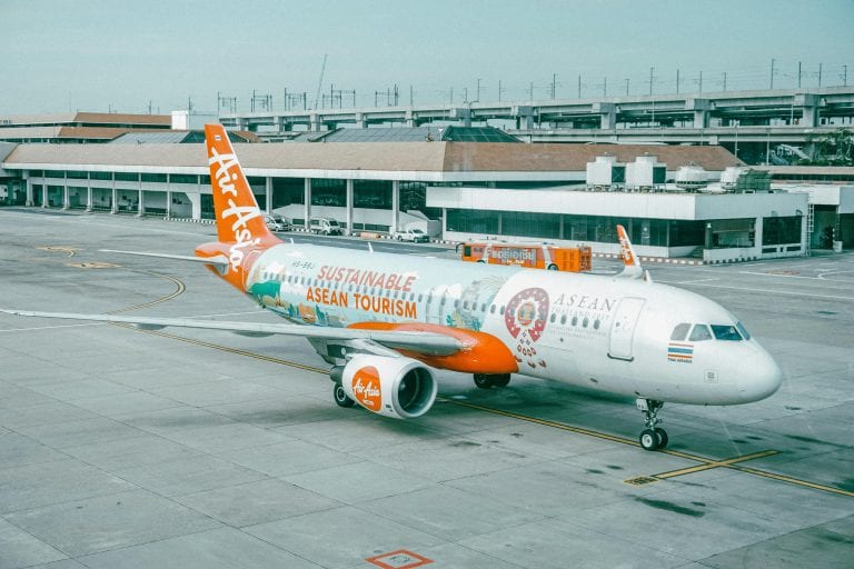 AirAsia airplane promoting sustainable ASEAN tourism parked at an airport.
