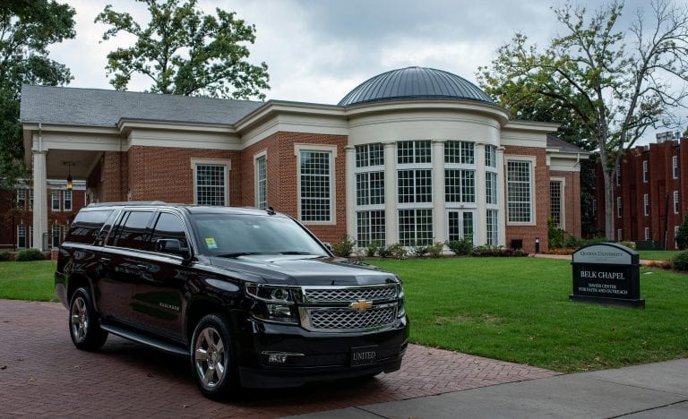 Black SUV parked in front of the elegant Belk Chapel at Queens University, showcasing architecture.