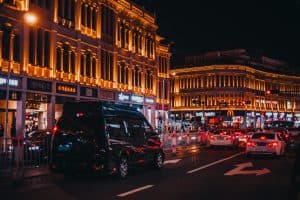Illuminated city street with busy nightlife, showcasing vibrant architecture and bustling traffic.
